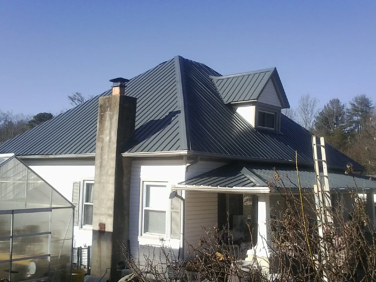 Dark blue standing seam metal roof on a white farmhouse with dormer — Slate & Tile Roof Repair by Roofing Brothers in Deerfield