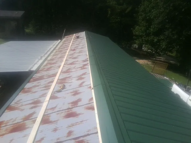 Old rusted panels beside newly installed green metal roofing — Wind Damage Roof Repair by Roofing Brothers in Deerfield